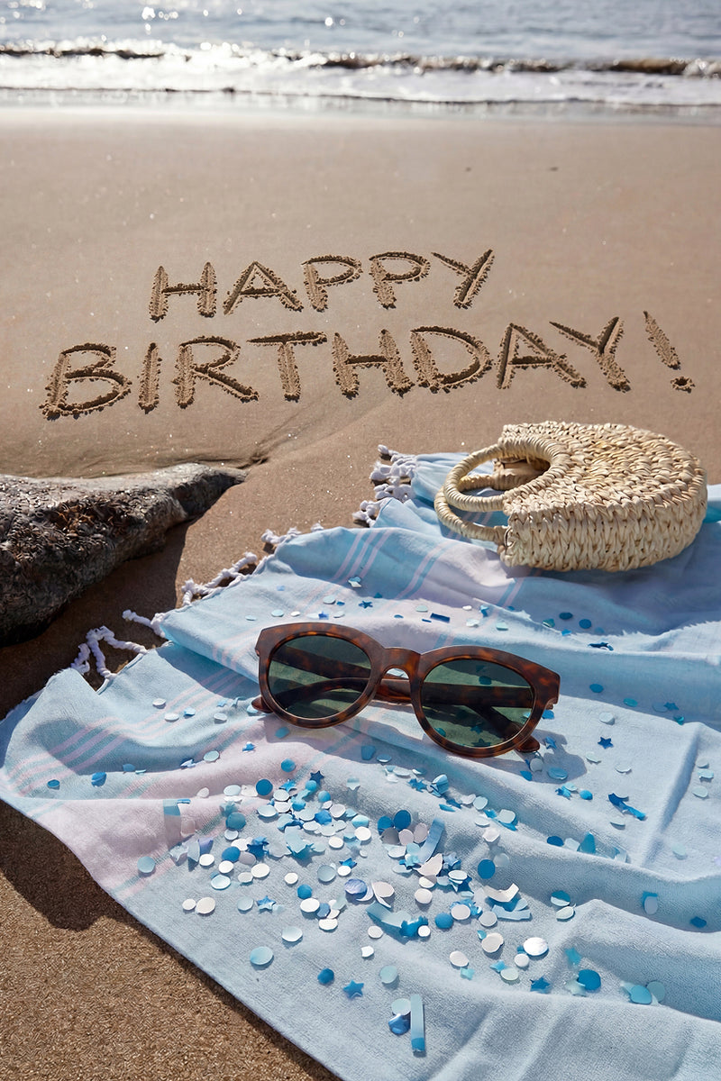 TOMS sunglasses on a blue blanket on a beach
