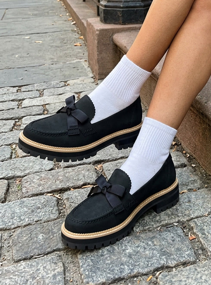Cara Bow in black leather on foot