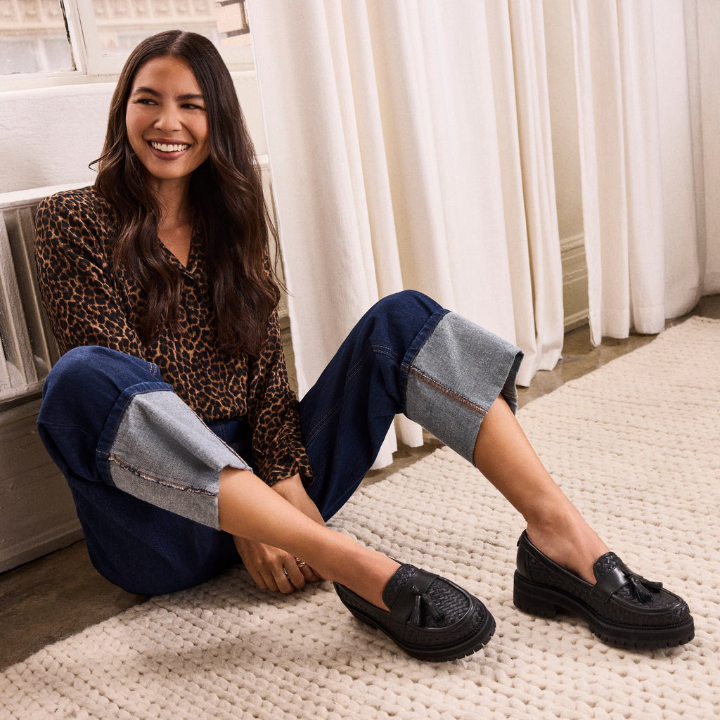 On figure image of the black woven faux leather with tassel Cara loafer
