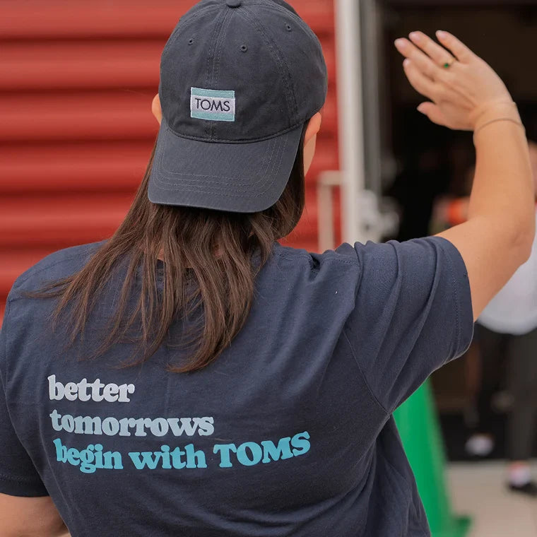 TOMS-teamlid met shirt met de tekst “betere toekomst begint met TOMS”